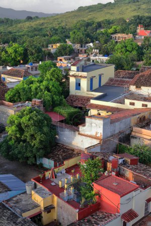 Trinidad, Cuba-October 12, 2019: Early sunset, NE-wards view from the San Francisco Church belfry over the mostly red tile -some gray slabbed- roofs of the city's housing to the countryside outskirts.