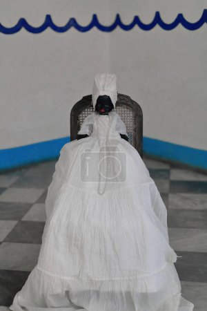Téléchargez les photos : Trinidad, Cuba-12 octobre 2019 : Vue depuis la rue d'un temple de Santeria situé dans une maison coloniale du XVIIIe siècle, dédiée à Yemaya la divinité de la mer représentée par une poupée noire vêtue de blanc. - en image libre de droit