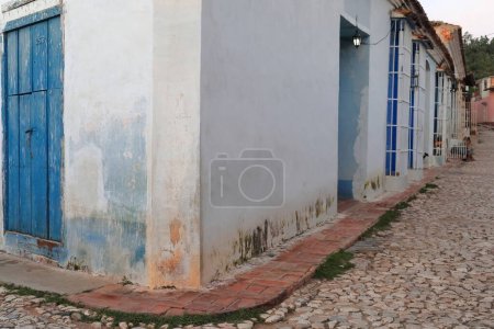 Trinidad, Cuba-October 12, 2019: Dilapidated facade of a colonial style house on an unidentified street corner near the Plaza Mayor Square with a peeling wooden door painted blue and the number 251B.