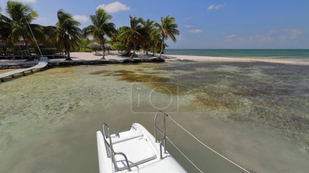 Photo for Transom steps and stern, left hull of a cruising catamaran moored off the white sand beach at the Cayo Iguana or Cayo Macho de Afuera Key anchorage, the disembarkment plankway at left. Trinidad-Cuba. - Royalty Free Image