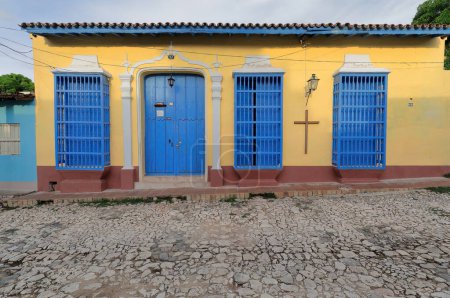 Fachada de color amarillo de casa colonial con puertas principales de madera azul y wicket y rejas torneadas, Calle Amargura Calle 108. Trinidad-Cuba-272