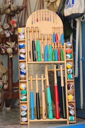 Photo for Items for playing baseball - bats, balls - displayed for sale on a wooden rack on the sidewalk outside a souvenir shop in the Plaza Mayor Square area, the city's colonial neighborhood. Trinidad-Cuba. - Royalty Free Image
