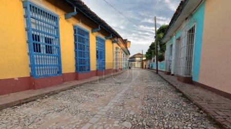 Photo for Trinidad, Cuba-October 13, 2019: Southeastward view along the cobbled Calle Real de Jigue Street flanked by colonial houses on both sides up to the Plaza Mayor Square and the Casa Aldeman Ortiz house. - Royalty Free Image