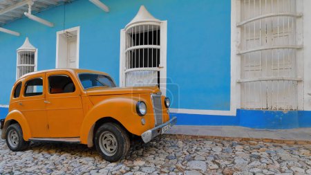 Téléchargez les photos : Trinidad, Cuba-13 octobre 2019 : Vue de côté, couleur carotte-orange vieille voiture classique américaine almendron, réservoir à manivelle Ford Prefect Salon 4 portes de 1952 stationné sur la rue Calle Desengano côté ouest. - en image libre de droit