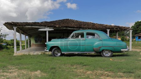 Foto de Trinidad, Cuba-14 de octubre de 2019: Old green American almendron classic car -Chevrolet Styleline Deluxe 4 door Sedan from 1952- stationed next to the train station building of the Manaca Iznaga Estate. - Imagen libre de derechos