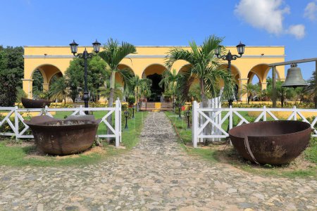 Trinidad, Kuba-14. Oktober 2019: Frontansicht, nach Süden ausgerichtete Fassade des kolonialen Landsitzes des Besitzers im Landgut Manaca Iznaga, gegenüber dem schmucken Vorgarten, in dem sich die ehemalige Glocke des Glockenturms befindet.