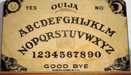 Photo for Santa Clara, Cuba-October 14, 2019: American made vintage ouija board from 1919 -The Mystifying Oracle- showing the usual Latin alphabet letters, numbers 0-9, words yes-no-goodbye, and various symbols - Royalty Free Image