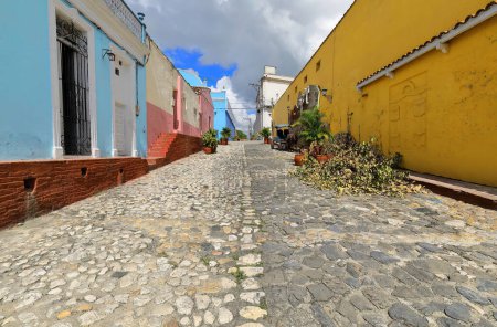 Sancti Spiritus, Cuba-October 15, 2019: Northwestward view along the cobbled Calle Padre Quintero Street up to the Teatro Principal Theater and buildings on the transversal Calle Maximo Gomez Street.