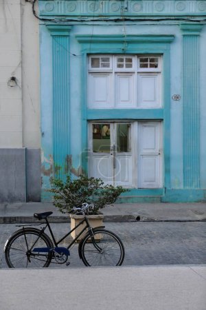 Camaguey, Cuba-October 15, 2019: Vintage bicycle parked leaning on the pink granite curbside of the cobbled Calle Marti Street, the north side of Parque Ignacio Agramonte Park fronting the Cathedral.