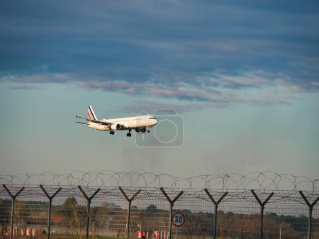 Photo for Passenger airplane is landing in runway. Protected area of international airport. Plane released landing gear flying over autumn trees. Arrival of charter flight to airport. Commercial Air Transport. - Royalty Free Image