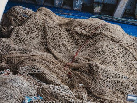 Foto de Red de pesca una pila de redes de pesca marrón en la cubierta de un barco azul. - Imagen libre de derechos