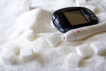 Glucometer on spilled sugar, excessive sugar consumption, diabetes concept