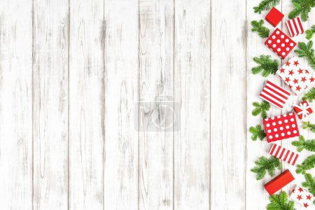 Foto de Frontera navideña. Caja de regalo y ramas de pino sobre fondo de madera blanca - Imagen libre de derechos