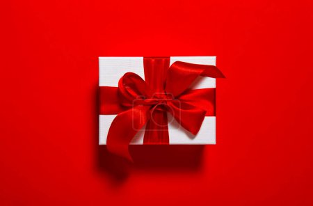 Foto de Tarjeta de regalo. Caja de regalo con lazo de cinta sobre fondo rojo - Imagen libre de derechos