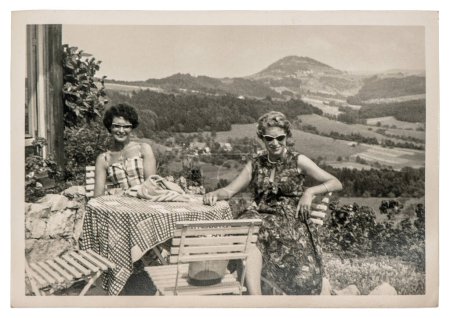 Foto de ALEMANIA - BERLÍN, 26 de noviembre de 2023: Foto antigua de dos mujeres vestidas de moda y gafas de sol al aire libre. Imagen vintage con grano de película original y desenfoque de ca. 1960 - Imagen libre de derechos