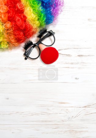 April Fool's Day clowning props. Clown costume accessories on white wooden background