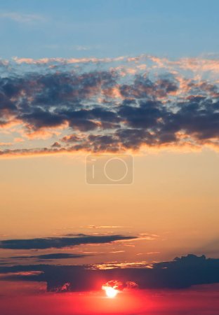 Téléchargez les photos : Lever de soleil rouge vif contre le ciel bleu. Photo verticale. - en image libre de droit