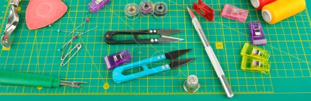 Photo for A set of sewing accessories laid out on a patchwork mat. Wide photo. - Royalty Free Image