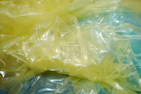 Photo for Part of crumpled cellophane of yellow color prepared for wrapping small metallic details of industrial machines over light blue surface - Royalty Free Image