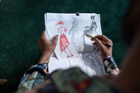 Téléchargez les photos : Above angle of hands of non-binary male fashion designer creating sketches of new apparel for spring and summer collection - en image libre de droit