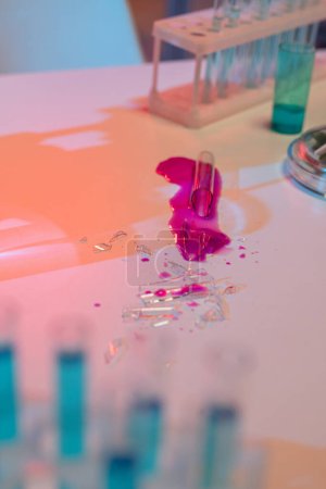 Téléchargez les photos : Shatters of broken glass flask with dangerous chemical substance of purple color on workplace of scientist in modern laboratory - en image libre de droit