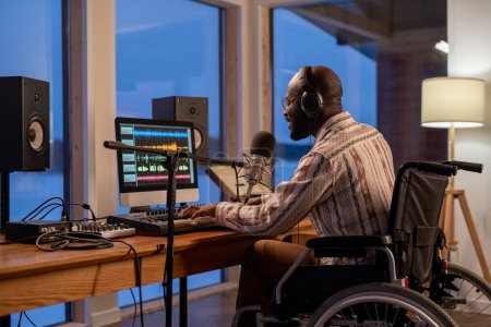 Photo for Happy young black man in wheelchair playing piano keyboard, singing and recording new song in studio or at home - Royalty Free Image