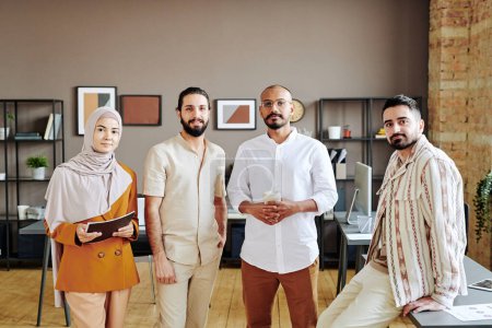 Téléchargez les photos : Group of young Muslim entrepreneurs in casualwear standing in front of camera against interior of spacious modern openspace office - en image libre de droit