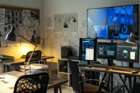 Téléchargez les photos : Corner of small office of FBI agency with set of criminal profiles hanging on board and large screen security camera on wall - en image libre de droit