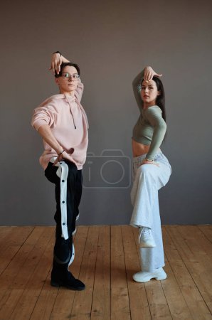 Téléchargez les photos : Two youthful vogue dancers in activewear keeping their legs bent in knee while working over new movements during training in studio - en image libre de droit