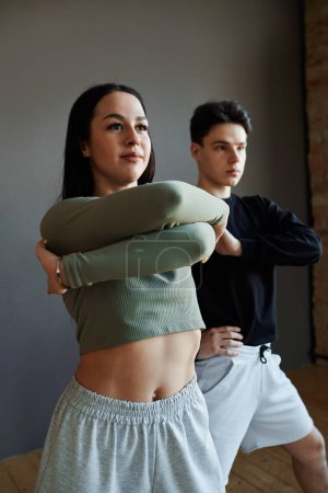 Téléchargez les photos : Two youthful stylish animator dancers in activewear performing vogue dance in studio or training new movements during repetition - en image libre de droit