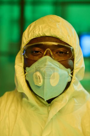 Photo for Contemporary black man in white protective coveralls, respirator and eyeglasses looking at camera during work in clinical laboratory - Royalty Free Image