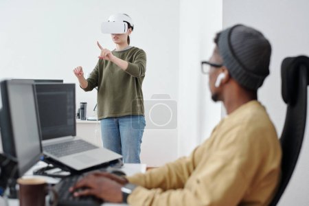 Photo for Contemporary young businesswoman in vr headset making virtual presentation in front of male colleague decoding data - Royalty Free Image
