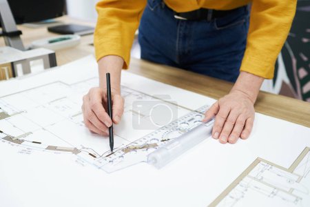 Téléchargez les photos : Gros plan de l'architecte à l'aide d'un crayon et d'une règle pour dessiner un plan sur la table au bureau - en image libre de droit