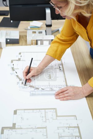 Téléchargez les photos : Gros plan du projet de dessin d'architecte femme mature avec crayon et règle à table - en image libre de droit
