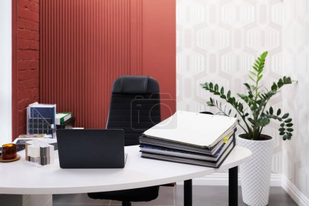 Photo for Workplace of designer with laptop and stack of folders on table at modern office - Royalty Free Image