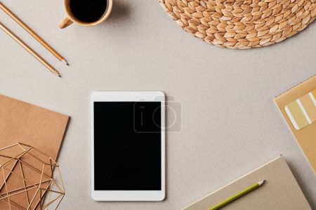 Photo for Flatlay of tablet surrounded by pencils, cup of coffee, paper, copybook and notebook over pastel grey background or workplace of designer - Royalty Free Image