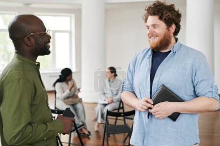 Foto de Feliz joven interracial hombres en ropa de casualwear tener discusión contra las mujeres que se comunican antes o después de la sesión psicológica - Imagen libre de derechos