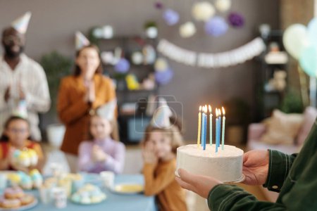 Foto de Primer plano del padre llevando pastel con velas quemadas para felicitar a su hijo con el cumpleaños - Imagen libre de derechos