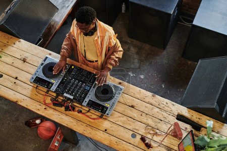 Oben Ansicht des jungen afroamerikanischen männlichen Musikers, der neue Musik bei lesire macht, während er Plattenspieler am DJ-Set berührt und Sounds mixt