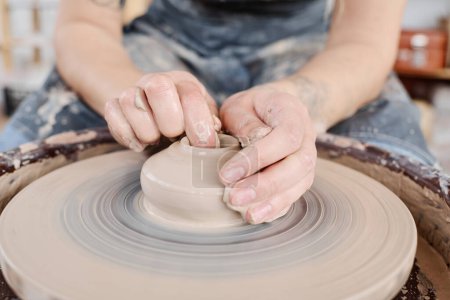 Téléchargez les photos : Mains de jeune potier femelle sur argile brute article sur roue de poterie rotative lors de la création de nouvelles faïences à vendre dans un atelier artisanal - en image libre de droit