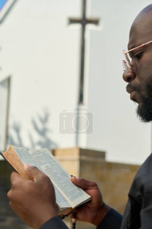 Foto de Primer plano del predicador afroamericano con versículos abiertos de lectura de la Biblia mientras especulan sobre su significado o se preparan para el sermón - Imagen libre de derechos