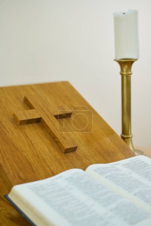 Photo for Part of pulpit with cross, burning candle and open Gospel with verses about life and ministry of Jesus Christ and His disciples - Royalty Free Image