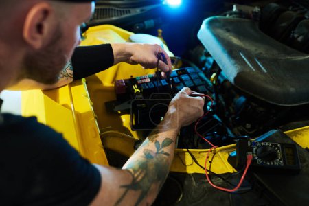 Téléchargez les photos : Mécanicien de service de maintenance effectuant des diagnostics techniques de moteur de voiture et d'autres pièces à l'aide de multimètre numérique - en image libre de droit