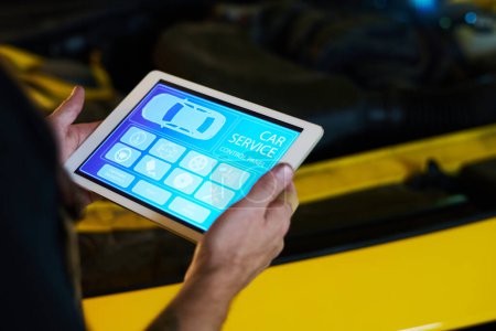 Photo for Hands of male mechanic of maintenance service holding tablet with homepage with icons on screen while standing by car - Royalty Free Image
