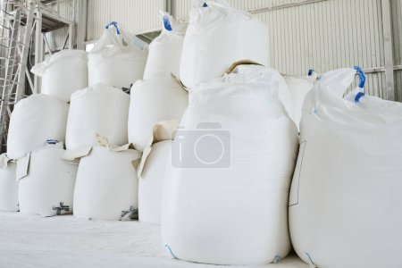 Photo for Heaps of huge white sacks containing loose raw materials prepared for production process in spacious warehouse or storage room - Royalty Free Image