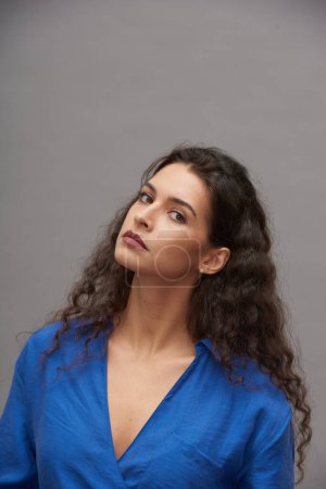 Photo for Young beautiful fashion model with trendy makeup bending her head slightly aside and looking at camera against grey background - Royalty Free Image