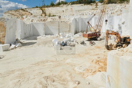 Photo for Part of spacious marble quarry surrounded by thick white rock walls and two construction machines working on the territory - Royalty Free Image