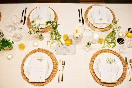 Téléchargez les photos : Vue de dessus d'une partie de la table de dîner servie avec assiettes, serviettes, verres à vin, citrons, fleurs et bougies préparés pour la fête de mariage - en image libre de droit