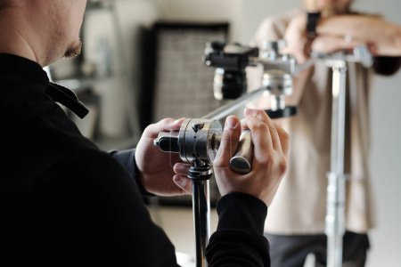 Téléchargez les photos : Mains de jeune photographe ou assistant réglage curseur métallique pour steadicam tout en se préparant pour le tournage de nouvelles publicités - en image libre de droit