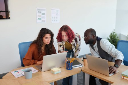 Téléchargez les photos : Groupe de jeunes collègues multiculturels en casual wear conseil sur un nouveau projet d'entreprise lors de la préparation de sa présentation - en image libre de droit